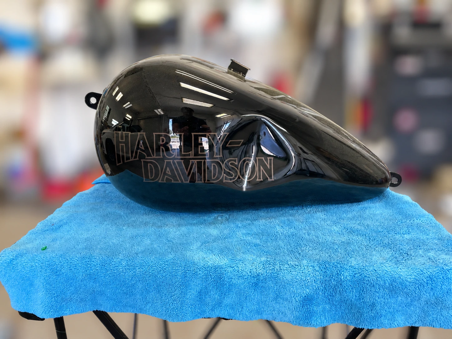Black Harley-Davidson fuel tank with a large dent before repair